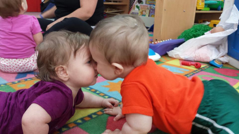 Two Babies on the floor socailizing by rubbing noses