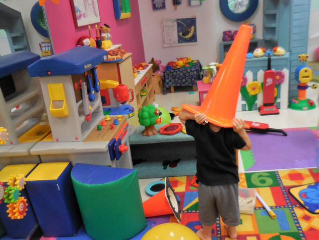 Preschool boy playing with construction cone on his head in the classroom