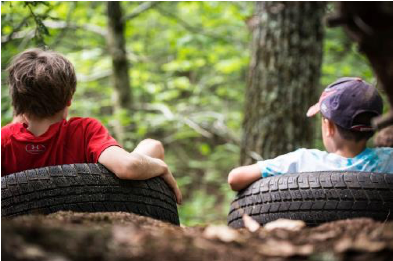 Two boys lying back on old tires in the forest on the ground