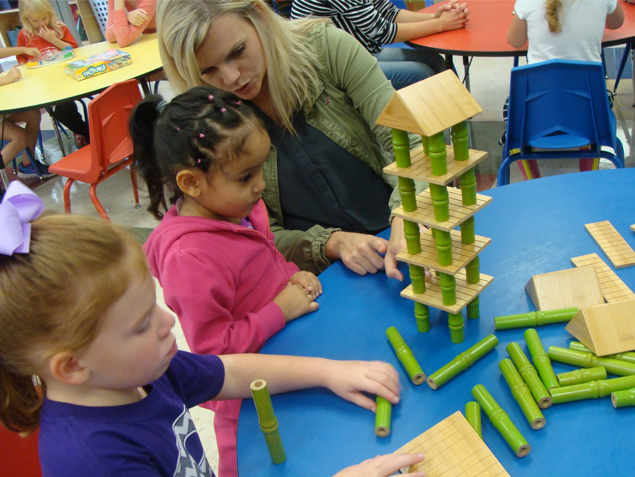 Student teacher working with two children and building blocks on a table