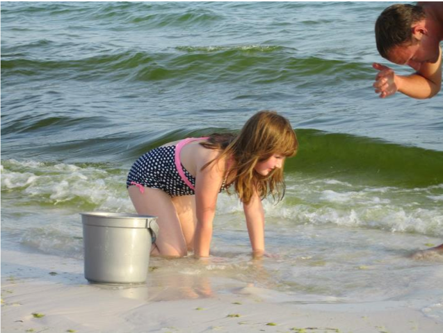 Girl digging in the sand at the ocean