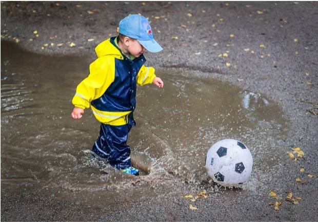 boy in a puddle with a soccer ball
