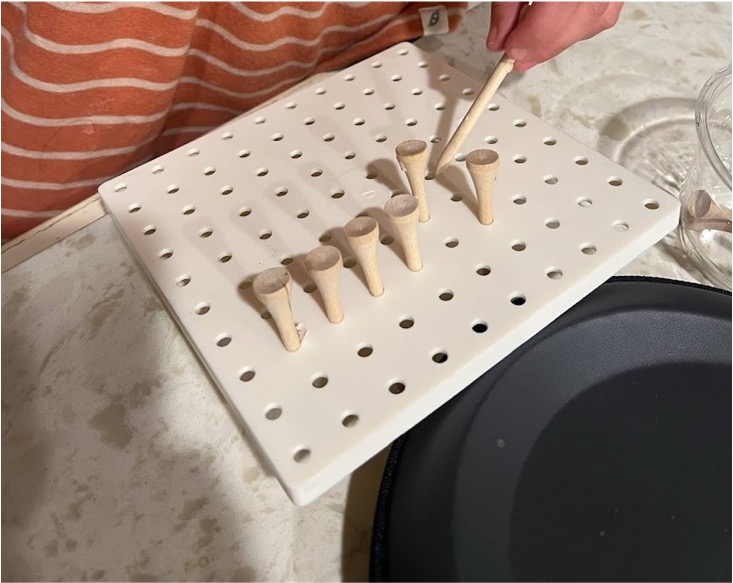 Placing golf tees into a pegboard.